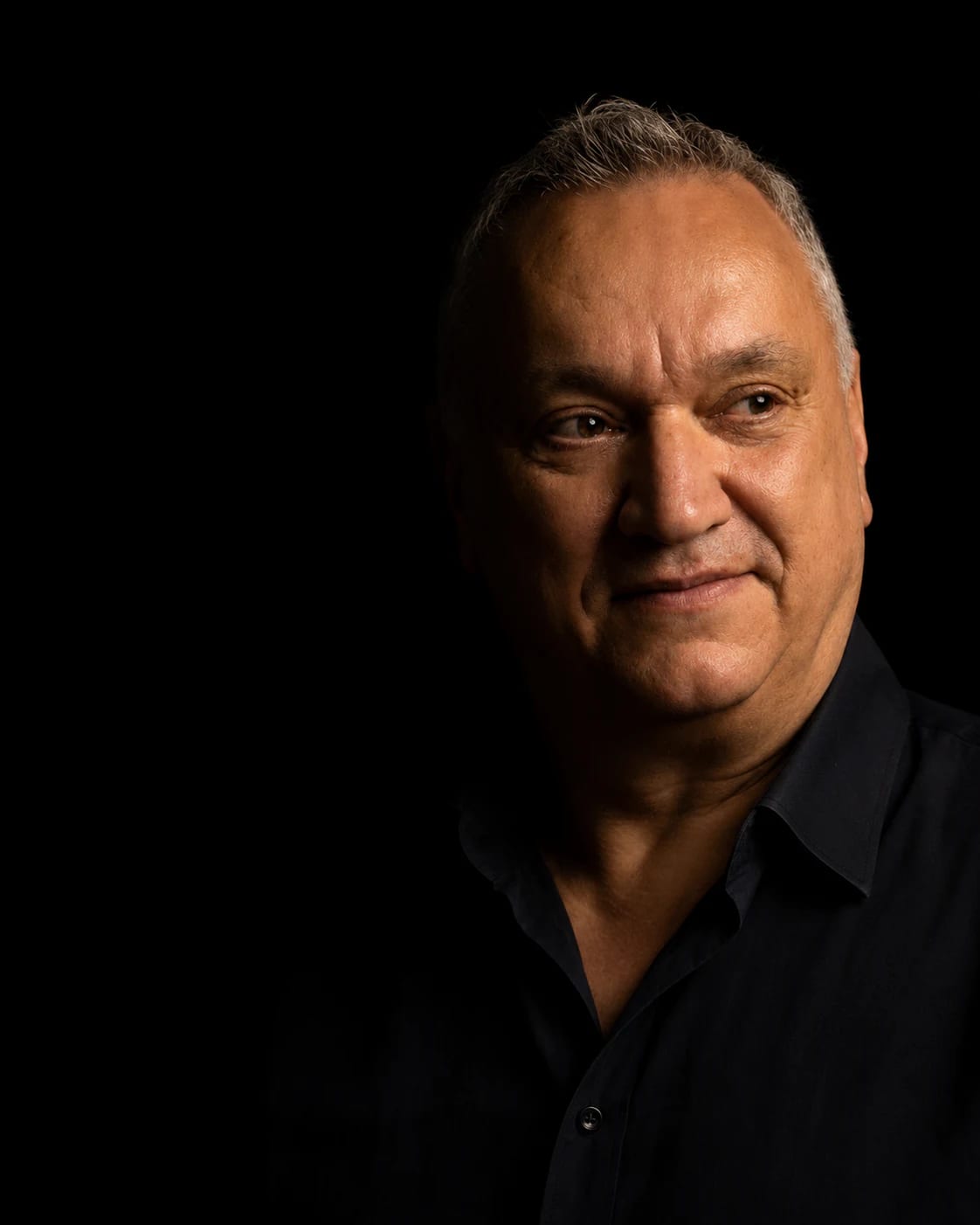 Giuseppe Daloiso, ritratto: il viso illuminato di taglio da una sola luce calda, il resto in ombra su fondo nero.